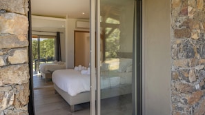 Un dormitorio con una cama grande, una puerta de vidrio que da a un balcón y paredes de piedra.