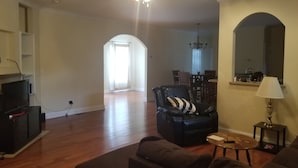 A spacious living room with hardwood flooring, a ceiling fan, a black leather armchair, a brown sofa, and a dining area in the background. -  One level ranch home.
Close to lake and park,bicycle lane, walking trail . (Knoxville)