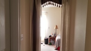 A narrow hallway with beige walls and a door on the left. There is a bed with a red blanket and a lamp in the room at the end of the hallway. -  One level ranch home.
Close to lake and park,bicycle lane, walking trail . (Knoxville)