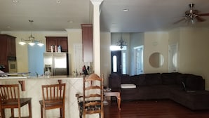 A modern kitchen with a central island, wooden chairs, a dark-colored sofa, and a ceiling fan. -  One level ranch home.
Close to lake and park,bicycle lane, walking trail . (Knoxville)