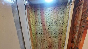 Un escalier étroit, avec un mur recouvert de carreaux orné d’hiéroglyphes, menant à un palier.