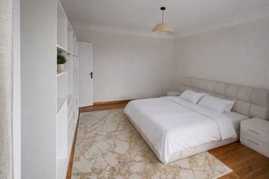 A bedroom with a bed, bedside tables, a wardrobe, and a hanging light fixture.