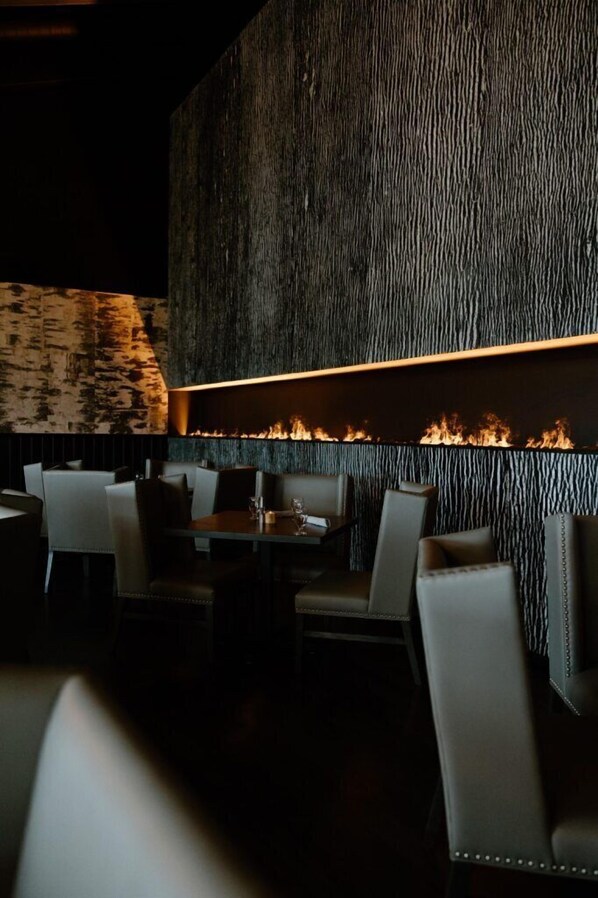 A restaurant interior with a fire feature, seating, and a textured wall.