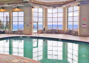 An indoor swimming pool with clear views of the ocean through large windows.