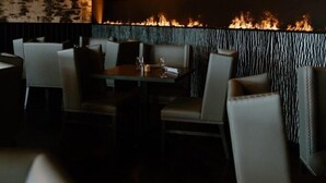 Interior de restaurante con una chimenea, asientos y una pared con textura.