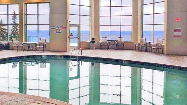 An indoor swimming pool with clear views of the ocean through large windows. - Lakeview Burlington Bay Two bedroom Suite (Two Harbors)