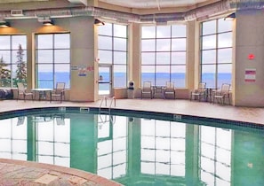 Ein Innenpool mit freiem Blick auf den Ozean durch große Fenster.