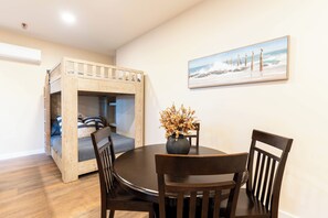 A room with a bunk bed, a dining table with chairs, a vase with flowers, and a painting on the wall. - Family Fun Suite - Arcade • Legoland • Beaches (Vista)