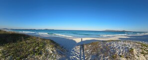 Een strand met heldere lucht, golven en verre landschappen.