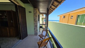 Ein Balkon mit Holzstühlen, gefliestem Boden und Meerblick.
