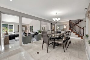 A spacious living area with a dining table, chairs, and a staircase.