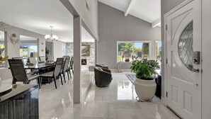 A spacious living area with a dining table, chairs, a sofa, and a large potted plant.