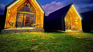Due cabine di legno con tetti a falde, ciascuna con un portico anteriore e un'area pranzo.