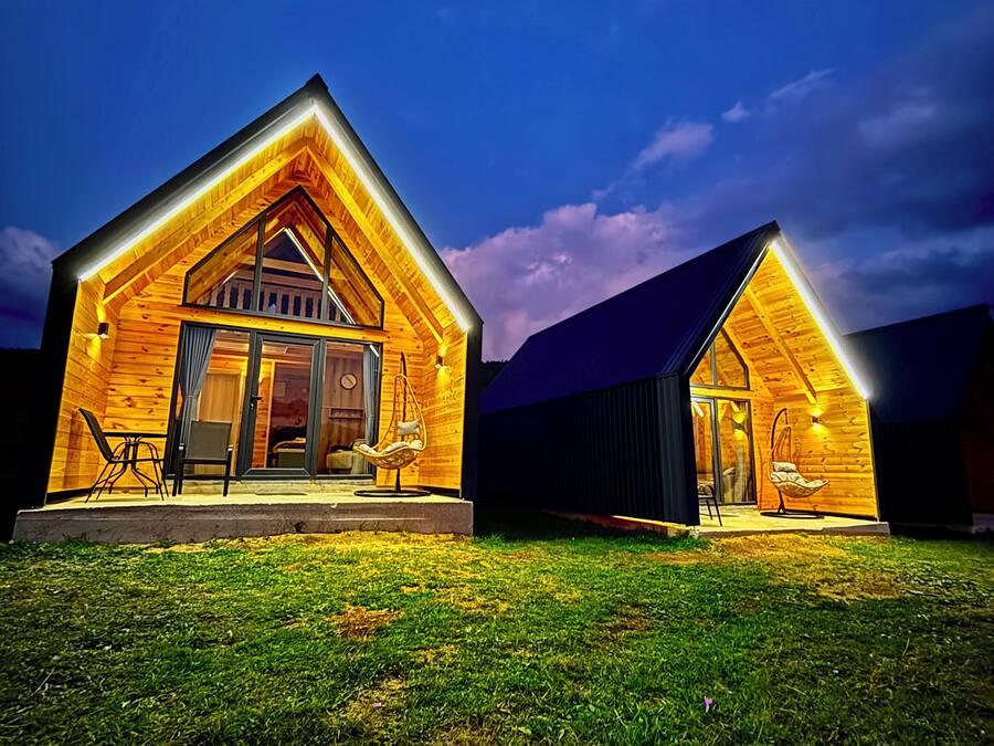 Deux cabanes en bois dotées de toits à deux versants, chacune comprenant une véranda à l’avant et un coin repas.