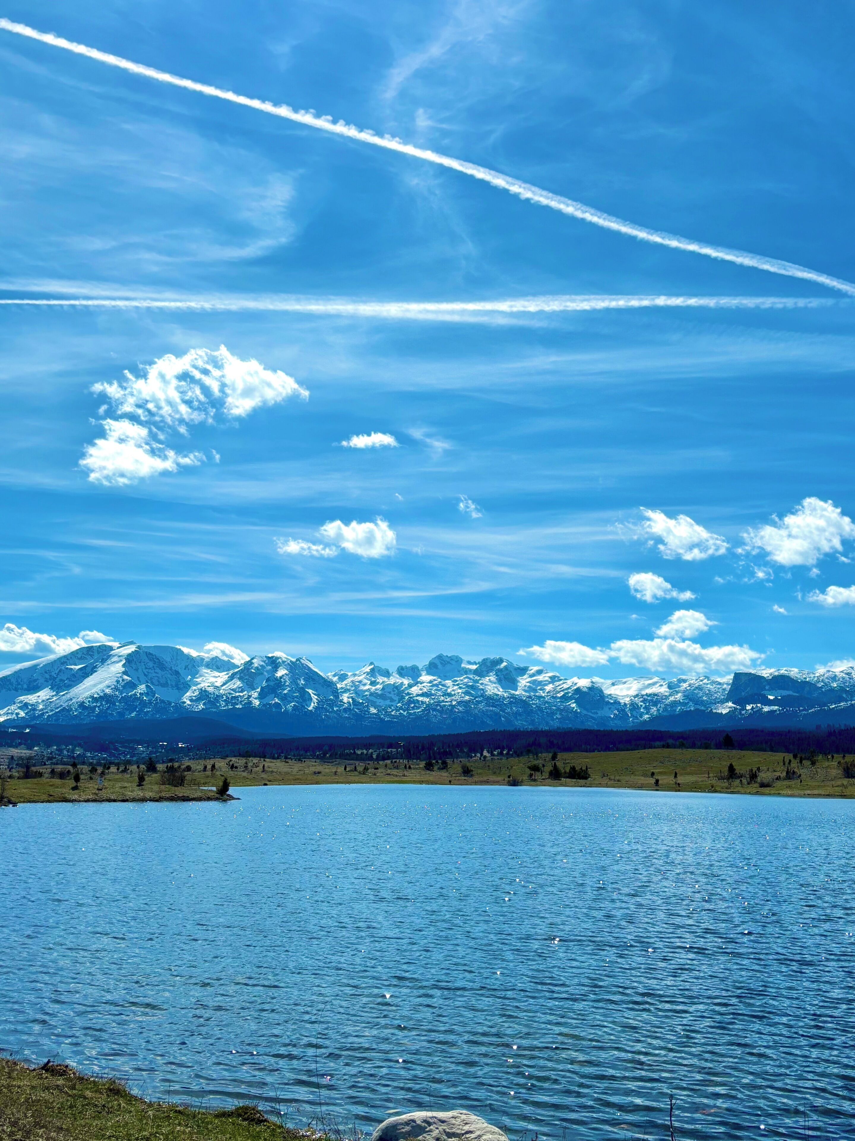 A lake with a mountain range in the background and a clear sky.