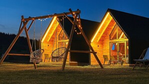 Una baita di legno con altalena e sedia amaca, con ampie finestre e interni luminosi.