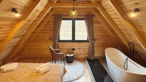 Una camera da letto mansardata accogliente con un letto grande, un angolo salotto e una vasca da bagno.