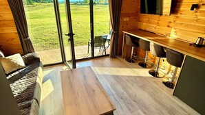Un'ampia stanza con un grande soffitto in legno, una panca di legno, un tavolo da pranzo e una TV montata a parete.