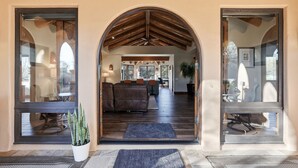 Una entrada con techo de madera y vista a un salón con sofá y mesa de comedor.
