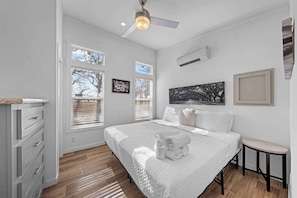 A bedroom with a bed, a ceiling fan, and a window with blinds.