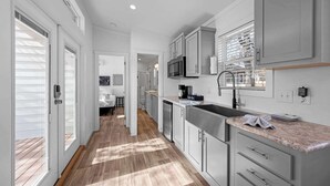 A modern kitchen with white cabinetry, a stainless steel sink, and a microwave. - The Resort at Fredericksburg Unit 16 (Fredericksburg)