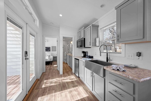 A modern kitchen with white cabinetry, a stainless steel sink, and a microwave.
