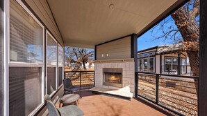 A covered deck with a fireplace, outdoor seating, and a view of the neighborhood. - The Resort at Fredericksburg Unit 16 (Fredericksburg)