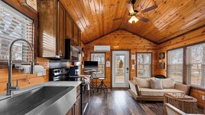 Interior de una cabaña de madera con cocina, comedor y zona de estar.
