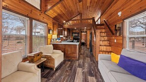 Interior acogedor de una cabaña con paredes de madera, una zona de cocina central y espacios de descanso.