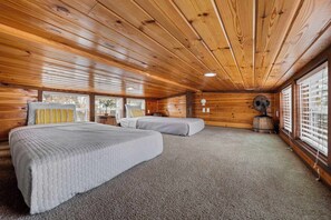 Eine Holzhütte mit zwei Betten und großen Fenstern.