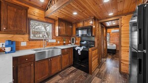 Una cocina estilo cabaña de madera con una isla grande, electrodomésticos de acero inoxidable y vistas a través de una ventana.
