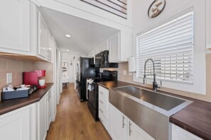 A kitchen with white cabinets, a stainless steel sink, and a red coffee maker. - The Resort at Fredericksburg Unit 28 (Fredericksburg)