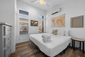 A bedroom with a large bed, a small stool, a world map, and a globe on the wall. - The Resort at Fredericksburg Unit 24 (Fredericksburg)