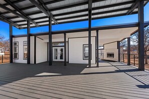 A covered outdoor area with a wooden deck, metal beams, and a white building with large windows. - The Resort at Fredericksburg Unit 24 (Fredericksburg)