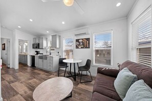 A modern kitchen with grey cabinets, a dining area with two chairs, and a brown sofa with cushions. - The Resort at Fredericksburg Unit 24 (Fredericksburg)
