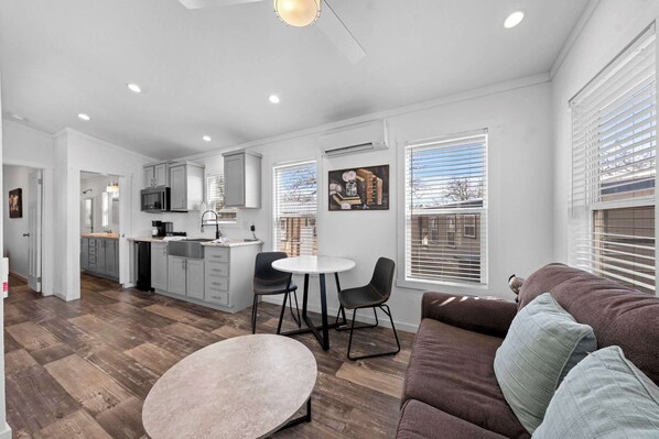 A modern kitchen with grey cabinets, a dining area with two chairs, and a brown sofa with cushions. - The Resort at Fredericksburg Unit 24 (Fredericksburg)
