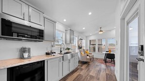 A modern kitchen with a dishwasher, coffee maker, and a dining area with a table and chairs. - The Resort at Fredericksburg Unit 13 (Fredericksburg)