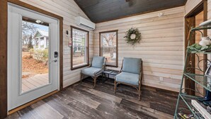 A cozy room with wooden walls, a ceiling fan, two chairs, a small table, and a decorative wreath. - The Resort at Fredericksburg Unit 3 (Fredericksburg)