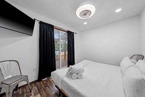 A hotel room with a bed, a chair, a window with curtains, and a ceiling fan. - The Resort at Fredericksburg Unit 3 (Fredericksburg)