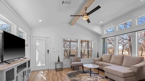 A spacious living room with a large flat-screen TV, a beige sofa, a small round table, and a ceiling fan. - The Resort at Fredericksburg Unit 17 (Fredericksburg)