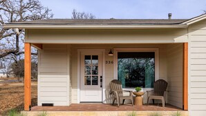 A house with a front porch, two chairs, a table, and a potted plant.