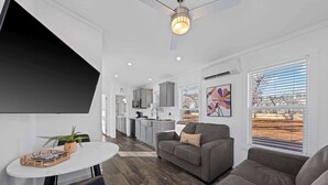 A modern living room with a sofa, a dining table, and a kitchen in the background. - The Resort at Fredericksburg Unit 30 (Fredericksburg)