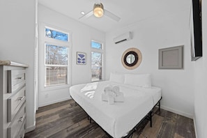 Ein Schlafzimmer mit einem Bett, einem Deckenventilator und einem Fenster mit Jalousien.