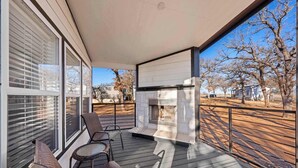 A covered outdoor area with a fireplace, seating, and a view of a tree-lined street. - The Resort at Fredericksburg Unit 30 (Fredericksburg)