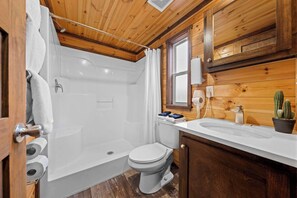 A wooden cabin bathroom with a bathtub, toilet, and sink. - The Resort at Fredericksburg Unit 2 (Fredericksburg)