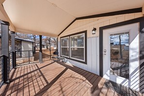 A covered deck with a wooden floor, a door with a glass panel, and a small table with chairs. - The Resort at Fredericksburg Unit 15 (Fredericksburg)
