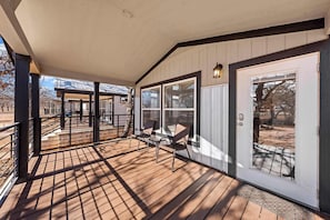 A covered porch with a wooden deck, a door with glass panels, and a small table with chairs. - The Resort at Fredericksburg Unit 20 (Fredericksburg)