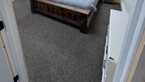 Un dormitorio con una cama de madera, una mesita de noche pequeña y una lámpara en el techo.