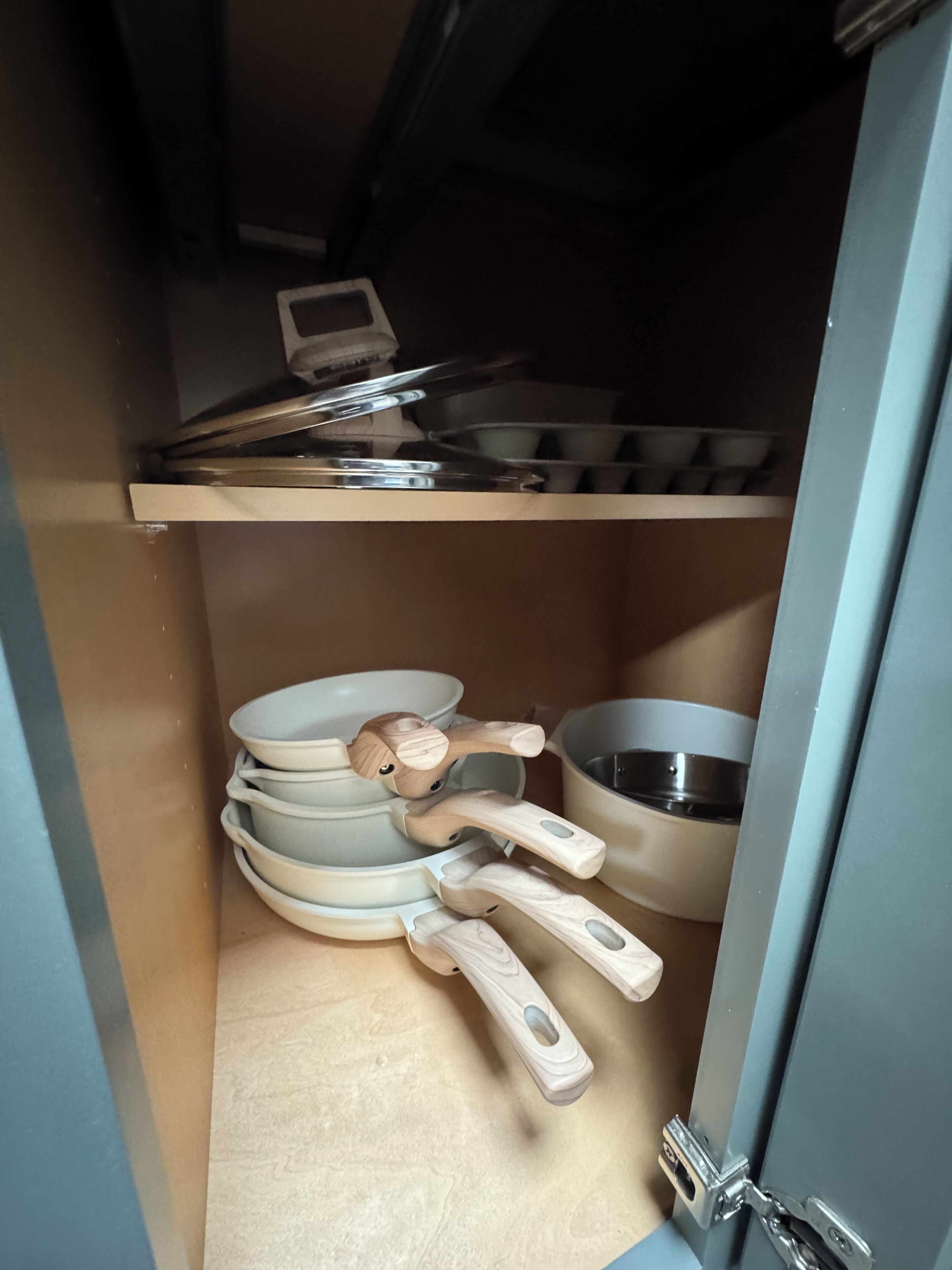 Een keuken met een houten plank waarop verschillende keukengerei en pannen staan.