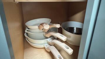 Een keuken met een houten plank waarop verschillende keukengerei en pannen staan.